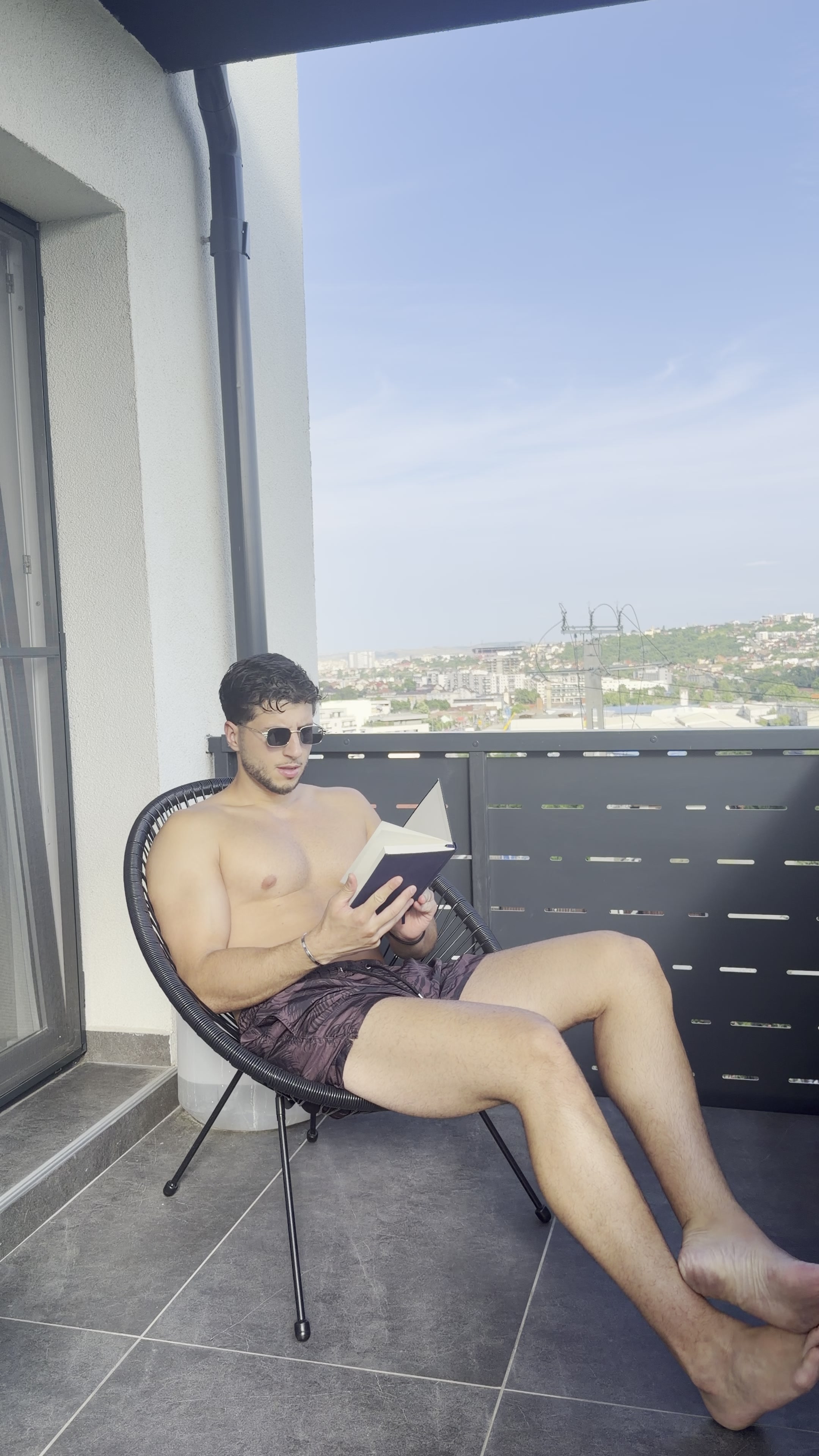 Man reading book on sunny balcony