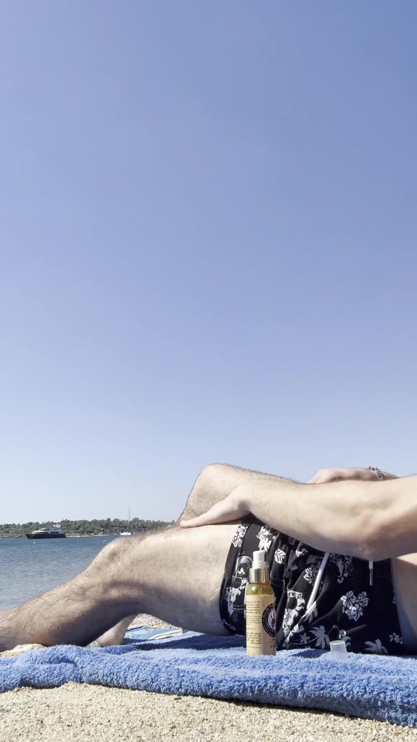 Man Applies Suntan Oil at Beach